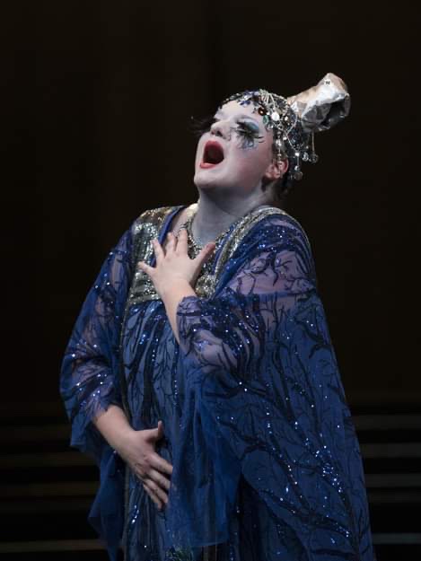Foto di Rebeka Lokar mentre si esibisce come Turandot in uno splendido abito blu. Si vede solo lei dietro a uno sfondo nero