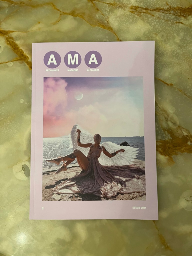 Copertina di AMA tutta rosa. Nel centro, la foto di Alexandra vestita come un angelo, sorride alla fotocamera seduta su una scogliera
