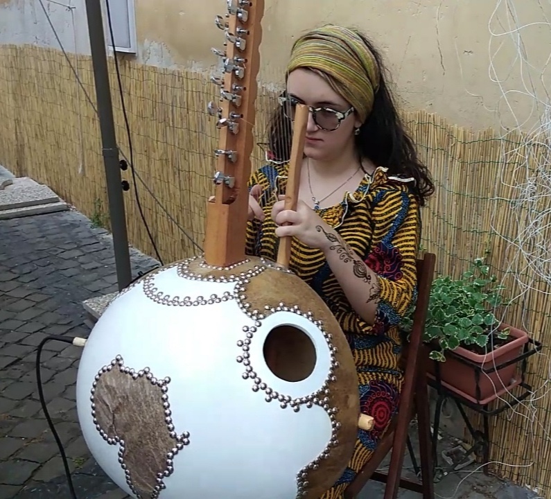 Clarissa con la cora. Indossa un vestito africano giallo con disegni rossi e celesti e striscie nere