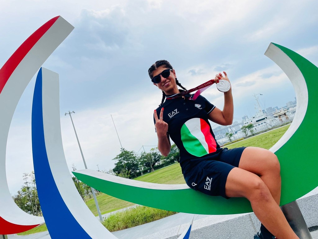 Anna seduta sopra il simbolo delle olimpiadi mentre stringe la sua medaglia￼