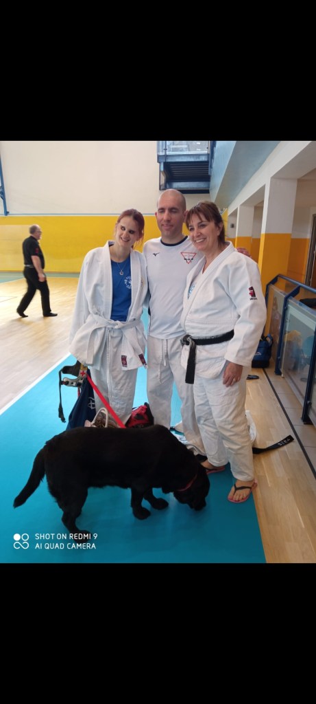 Roberto ed Elena in judogi posano assieme a Luigina Desopo e al cane guida Atena