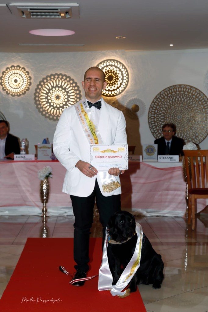 Roberto è Atena in posa davanti la giuria con la fascia da finalisti