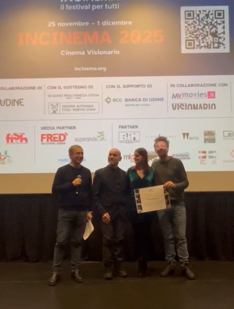 Roberto ed Elena eleganti posano assieme a FEderico Spoletti e il regista Alberto Fasulo davanti al maxi schermo del Cinema Visionario di Udine